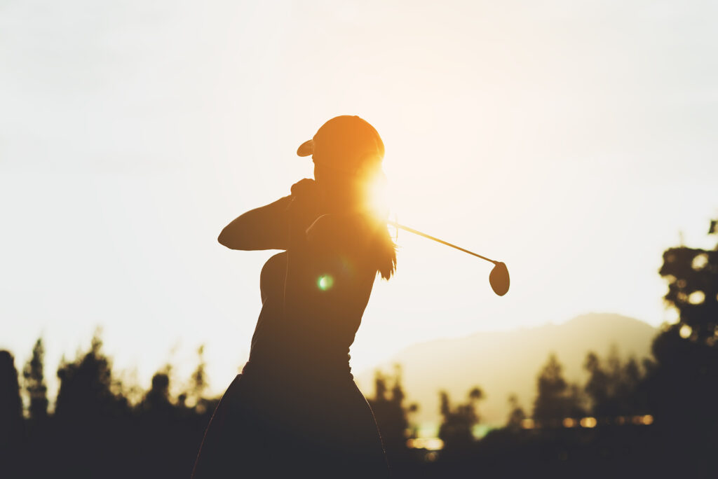 Silhouette of a young female swinging a golf club