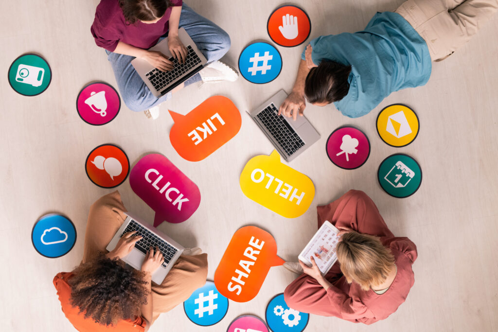 Above view of internet users sitting in circle among social media activity tags and icons and surfing net on devices
