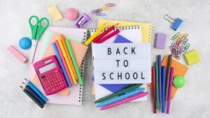 School supplies are piled on a white surface with a lightbox on top with words reading "back to school"